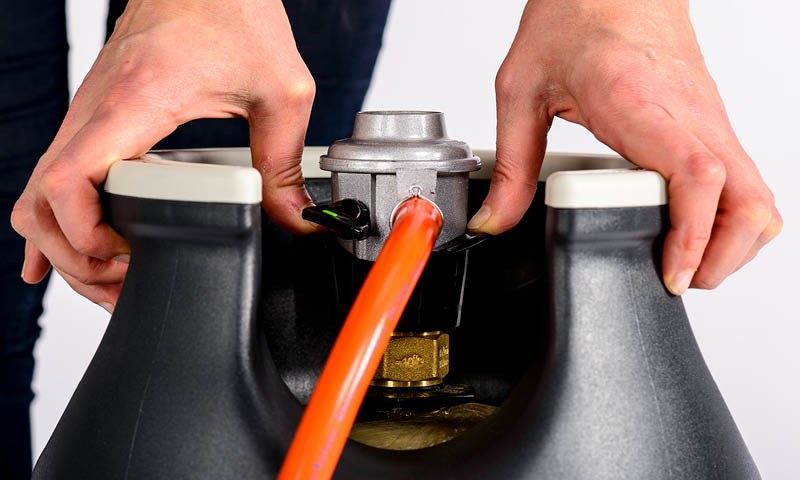 Hender som viser korrekt montering av gassflasken er kritisk for å unngå skader.