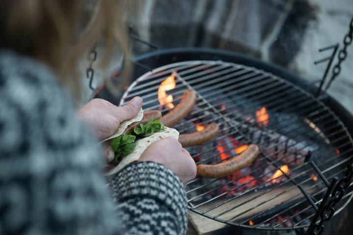 Person som griller pølser på Espegard bålpanne