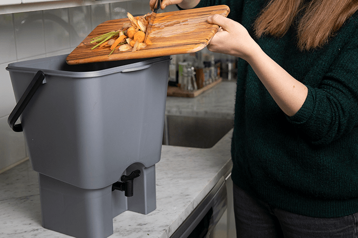 Bilde av dame som putter husholdningsavfall i kompostbøtte