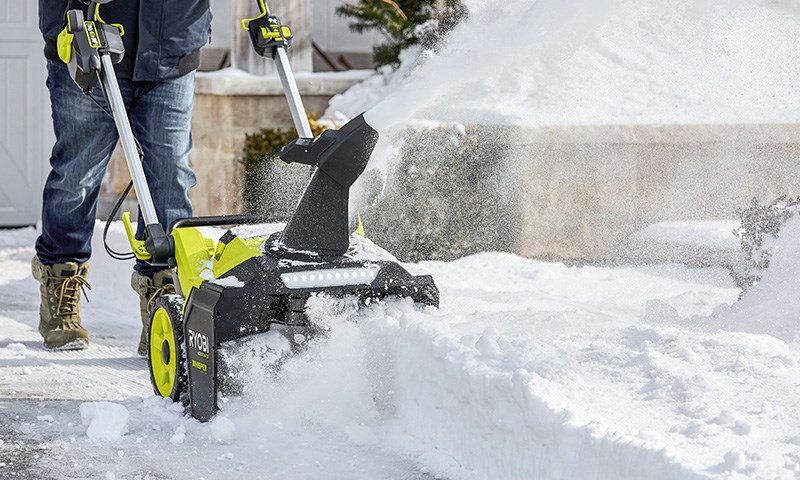 Mann med snøfreser på en snødekt vei